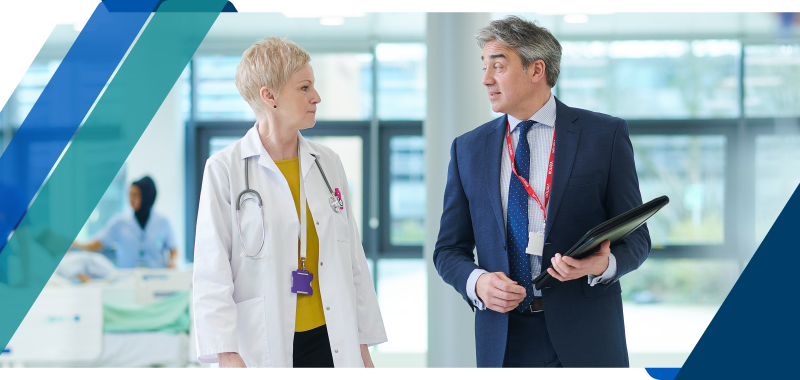 Two healthcare executives conversing in a facility hallway